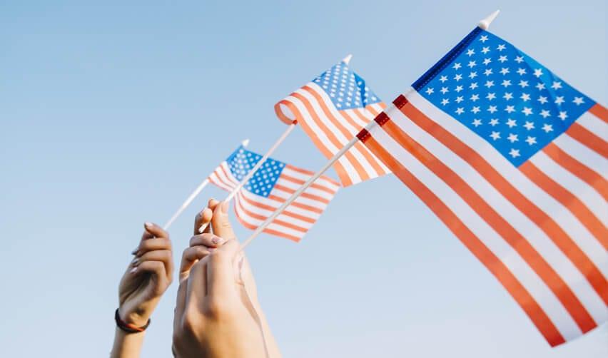 The EB5 investment visa is the best option for H-1B workers. We see people holding up American flags.