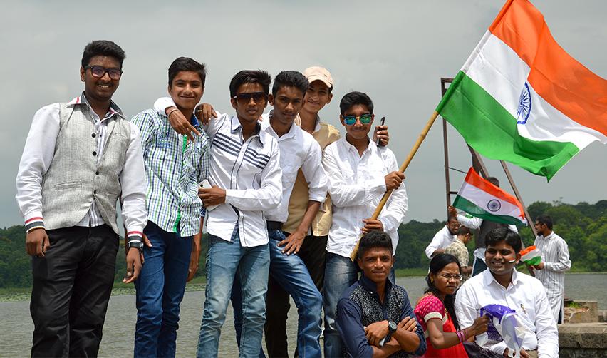 A group of people posing outdoors with Indian flags in their hands.