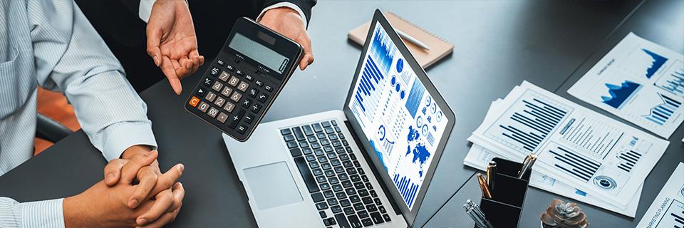 A regional center's management team working on a computer and a calculator to provide financial info about the investor's capital.