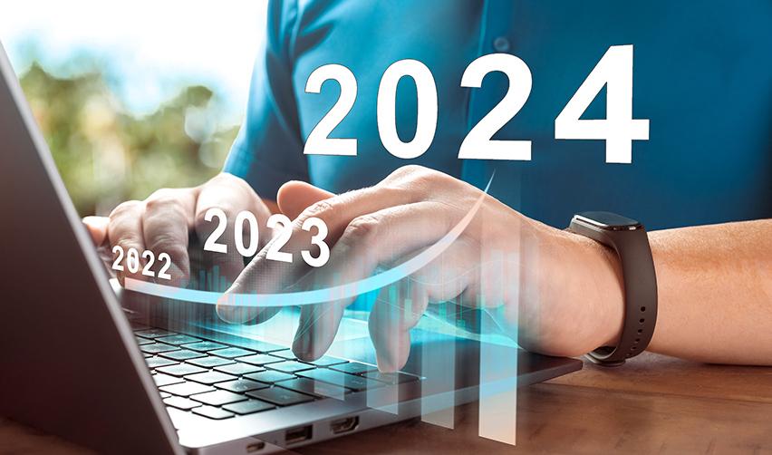 A person typing on a computer, with a graph icon and the numbers 2022, 2023 and 2024 hovering above it.