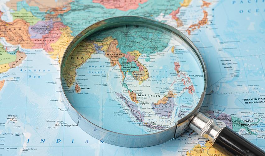 A magnifying glass on a world map, symbolizing EB5 visa issuance by country.