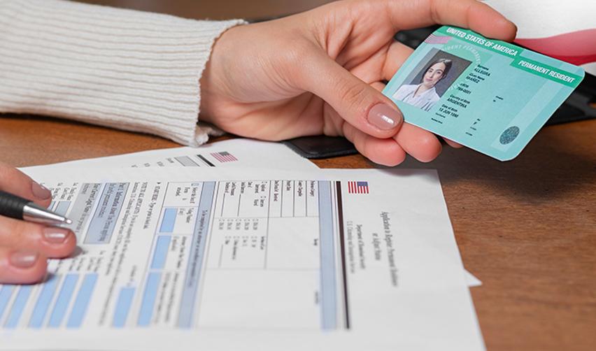 An EB5 investor filling out a form with her Permanent Resident Card (Green Card) in her hand.