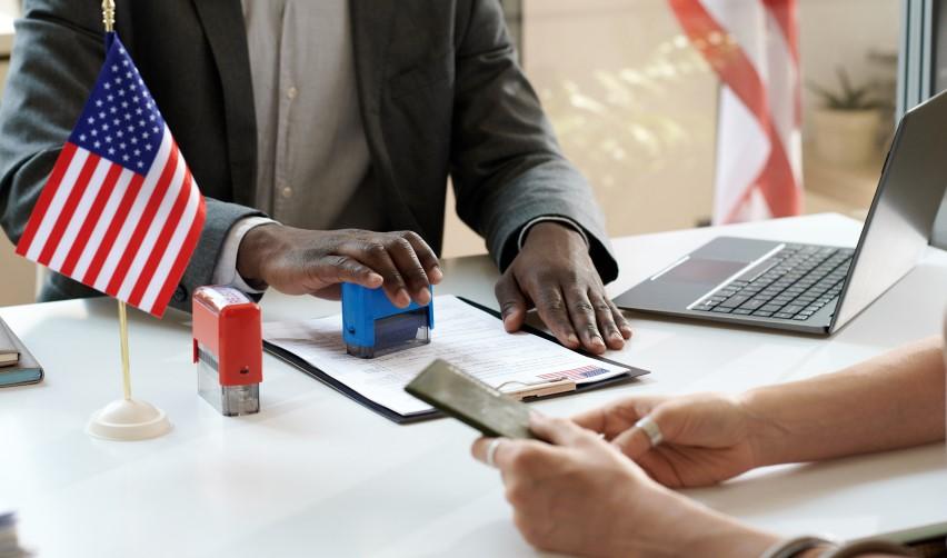 A United States Citizenship and Immigration Services officer stamping the visa application documents of an alien investor.