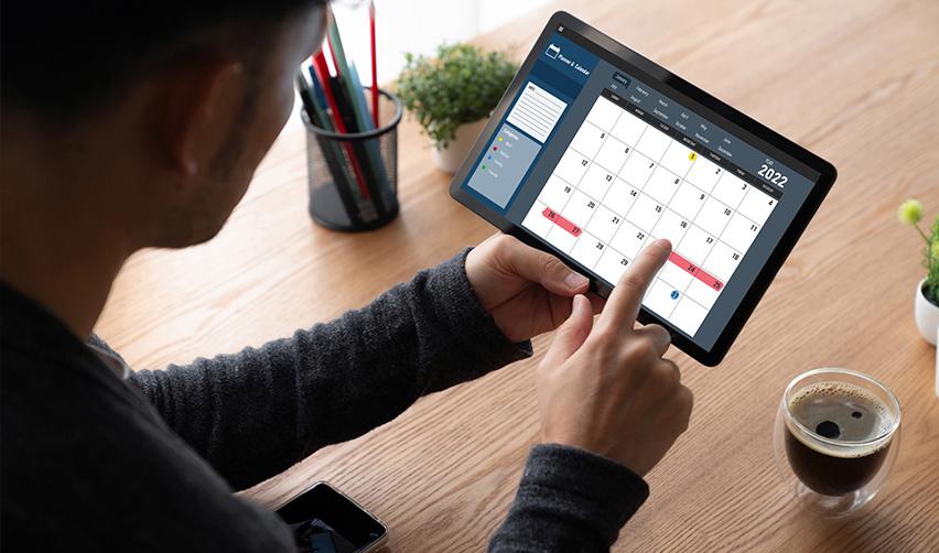 An immigrant investor looking at a calendar on his tablet, making a reschedule request for his existing biometrics appointment.