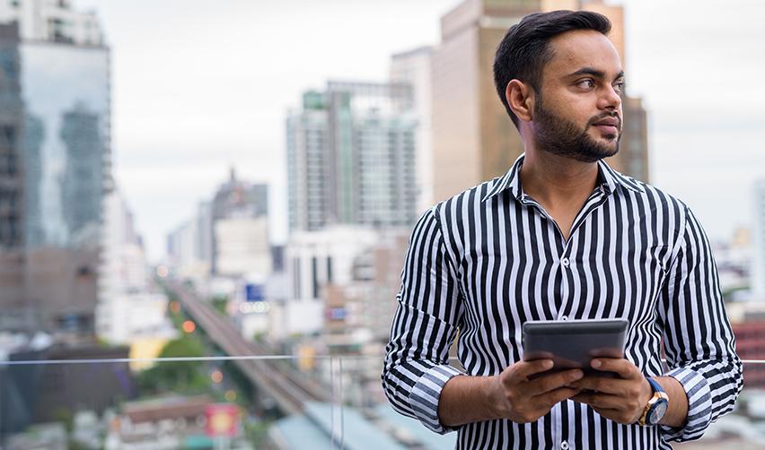 An H1b visa holder holding a tablet, considering his pathway to a Green Card.