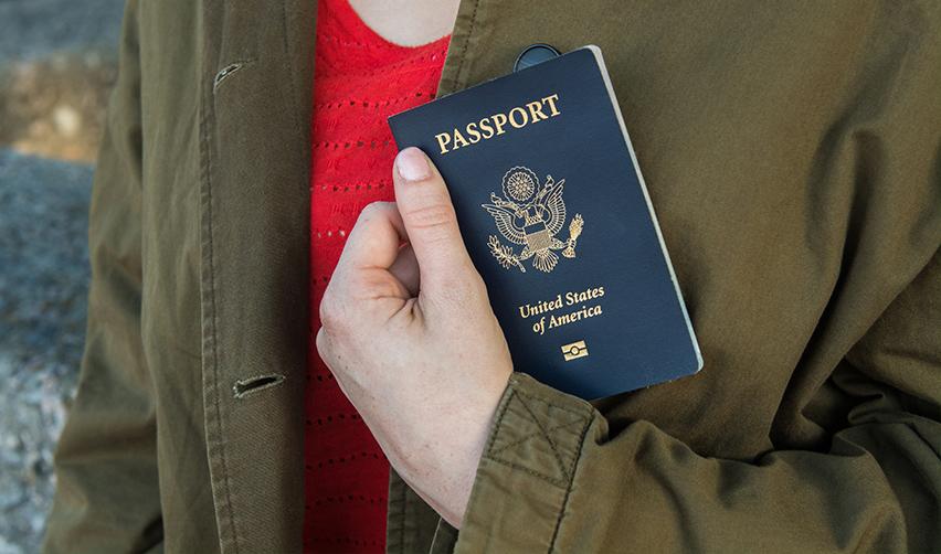 An EB5 investor holding a United States of America passport in her hand.