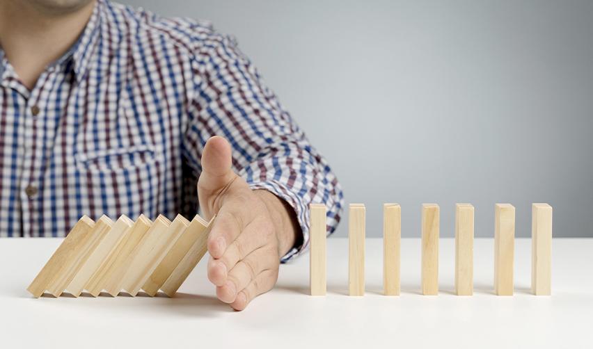 An EB5 investor stopping a row of domino blocks from falling, symbolizing risk management in EB5 projects.