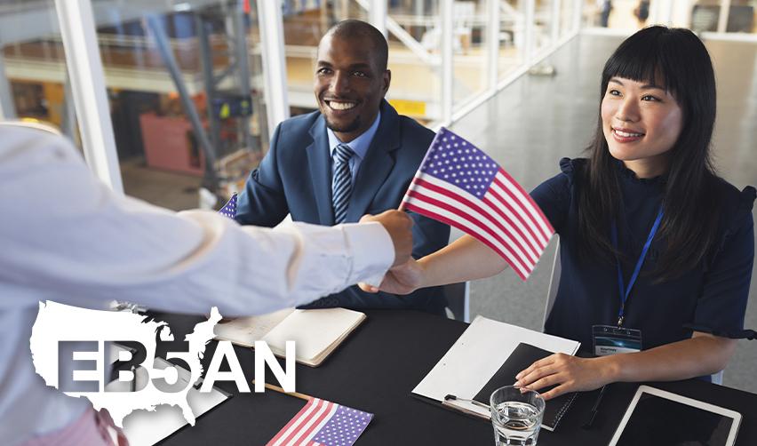 An EB5 investor holding the U.S. flag at an office, with the EB5AN logo on the corner.