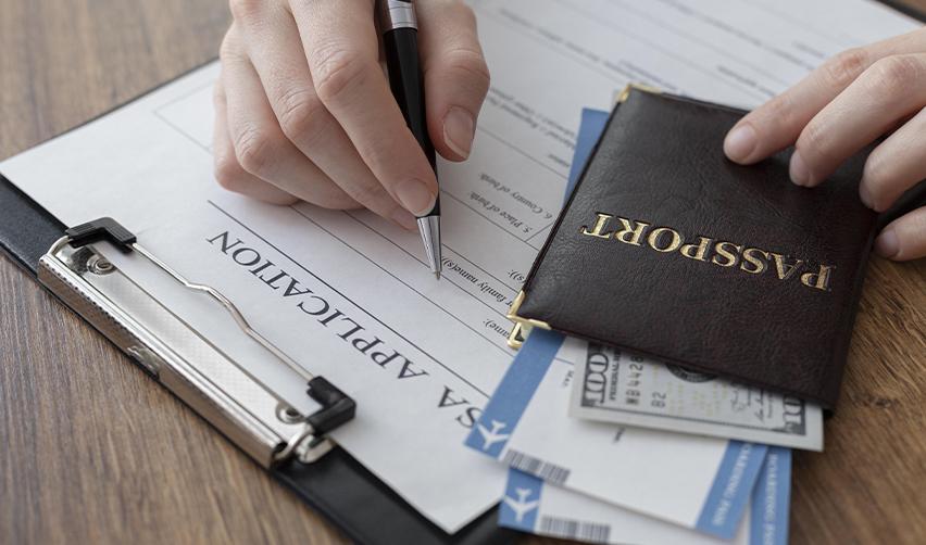 An Indian immigrant filling out a visa application form and providing additional documentation with his passport and some money in his hand.