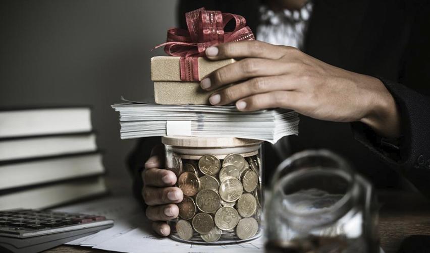 An EB5 investor holding a jar of coins and a giftbox in their hands, symbolizing EB5 source of funds.