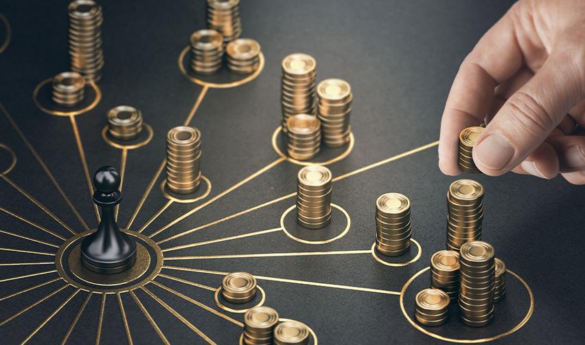 A hand placing stacks of coins in different piles, symbolizing investment diversification.