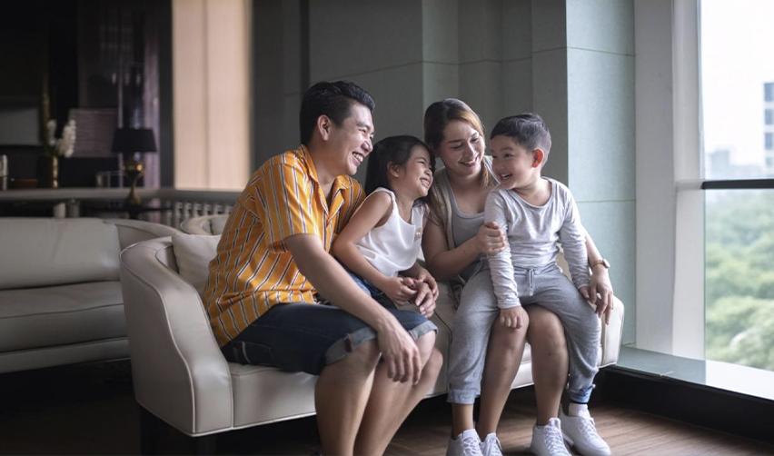 An EB5 investor and his immediate family members posing happily on a couch.
