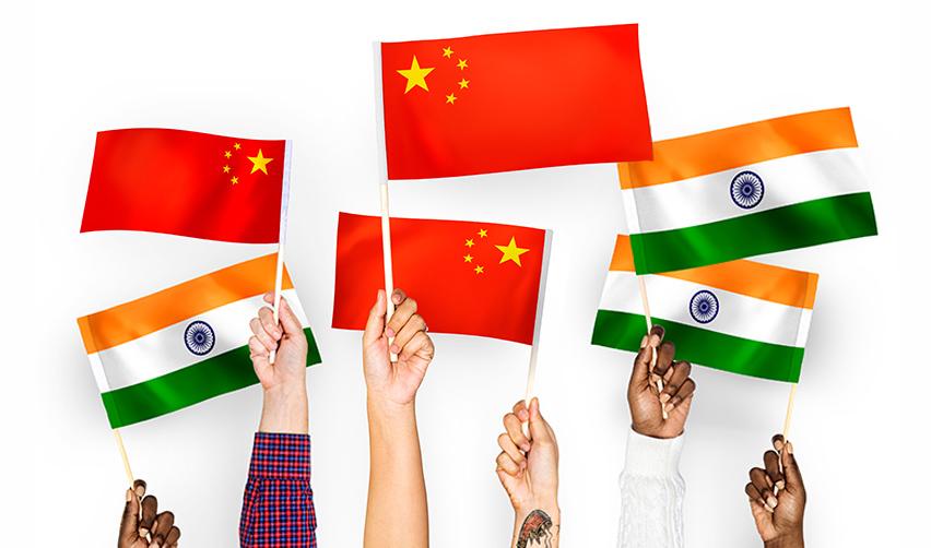 Hands of foreign nationals holding up Chinese and Indian flags, symbolizing high demand countries with limited visa availability.