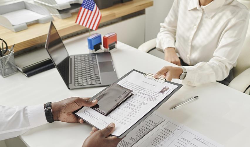 A foreign investor handing his EB5 visa application documents to a U.S. immigration office employee.