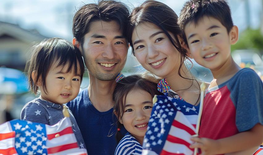 A group of EB5 regional center investors smiling at the camera with their family members holding U.S. flags.