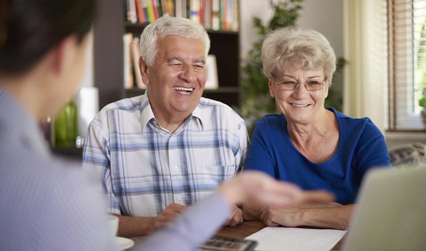 A smiling retired couple discussing EB5 visa investment options for permanent U.S. residency at an EB5 regional center office.