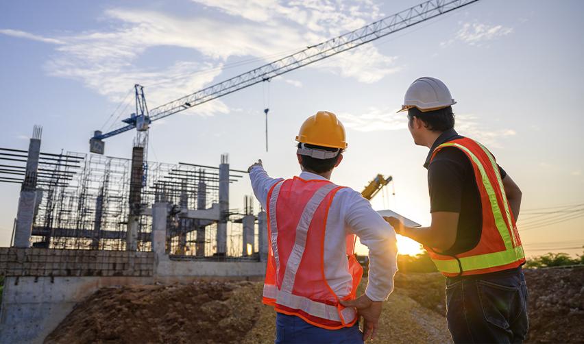 Two construction workers in safety vests and helmets inspecting an EB-5 project under development, illustrating ongoing construction as a key factor in reducing project delay risks for EB5 investors.