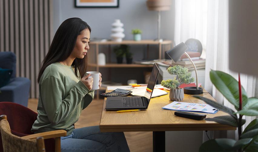 An EB5 green card holder enjoying working from home with a cup of coffee.