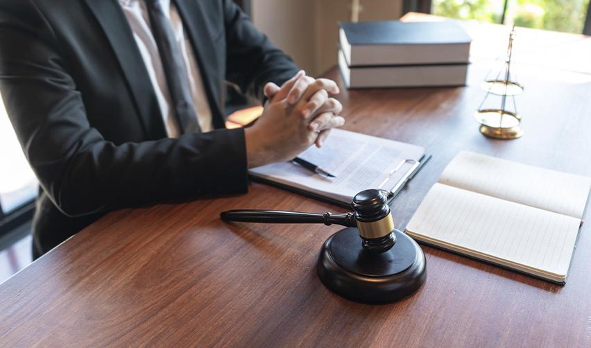 An immigration lawyer sitting at their desk with some visa application documents and a gavel, symbolizing what EB5 investors should expect from a mandamus complaint.