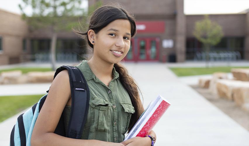 Young student outside a U.S. school, representing the educational benefits for children of EB5 Green Card holders.