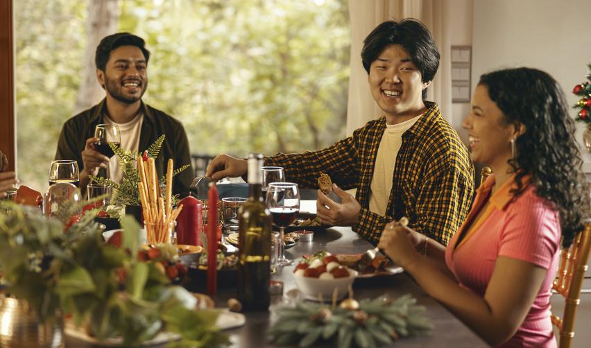 Smiling friends gathered around a Thanksgiving or holiday table, highlighting the community benefits of living in the U.S. with an EB5 Green Card.