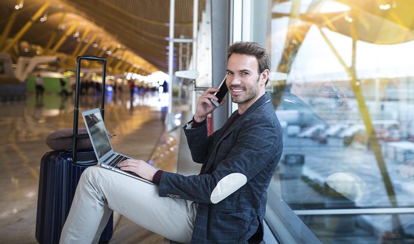 Entrepreneur with a laptop at an airport, highlighting the global expansion opportunities provided by the EB5 Immigrant Investor Program.