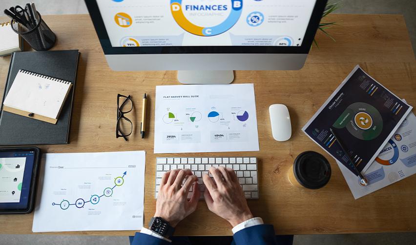 A professional working on financial charts and infographics at a desk, depicting improved business financing opportunities for EB5 investors in the US.