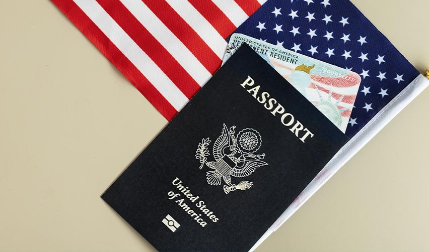 A US passport, green card, and American flag, illustrating the journey from an EB5 visa to becoming a lawful permanent resident in America.