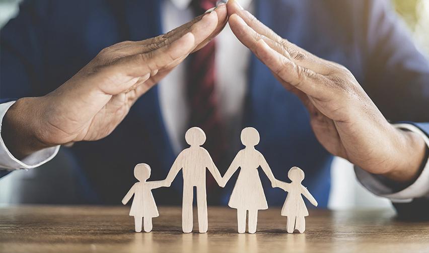 Wooden figurines of a family protected by hands symbolizing security, emphasizing the EB5 program's appeal for family-focused investors seeking a stable future in the U.S.