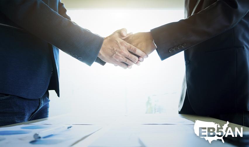 An EB5 investor shaking hands with a regional center principal or industry professional, with the EB5AN logo on the corner.