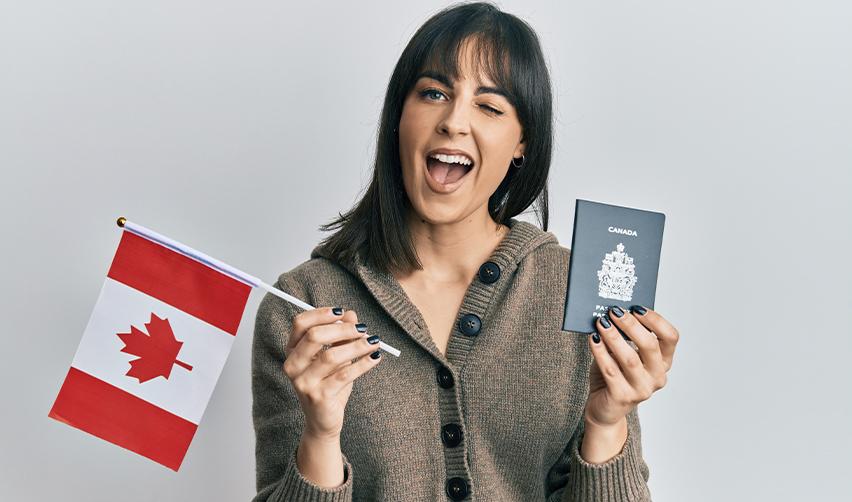 A cheerful young woman holding a small Canadian flag and a Canadian passport, smiling confidently. This symbolizes Canadians exploring U.S. green card options through EB5 investor visas and other pathways.