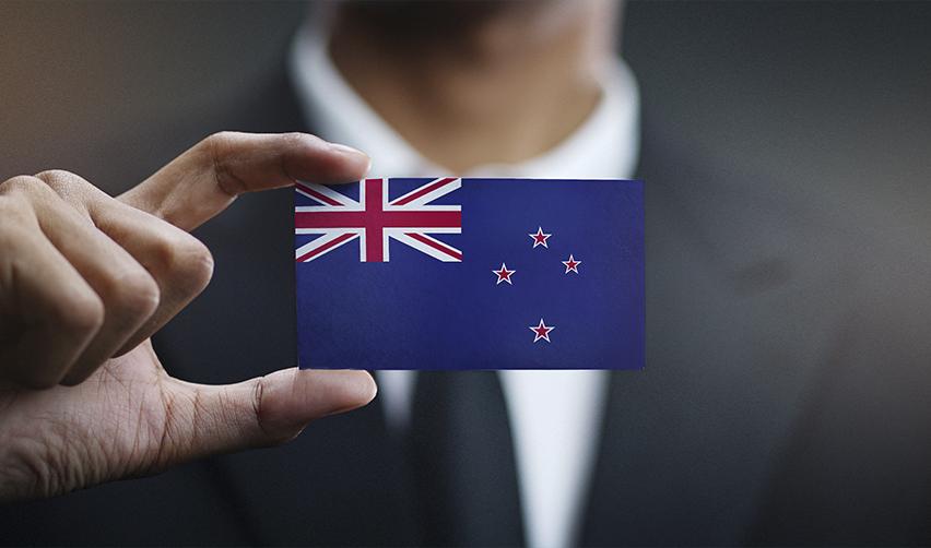 A New Zealand citizen with a valid passport holding a card with the NZ flag on it, symbolizing immigration from New Zealand to America.