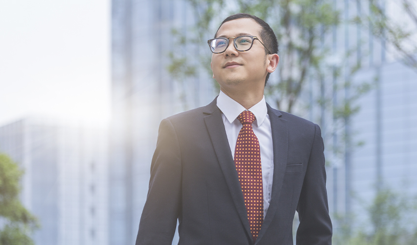 A confident businessman stands in front of a city skyline, representing the success of EB5 investors. A well-structured investment with an affiliated regional center and NCE improves investor confidence and increases the chances of obtaining a U.S. Green Card.