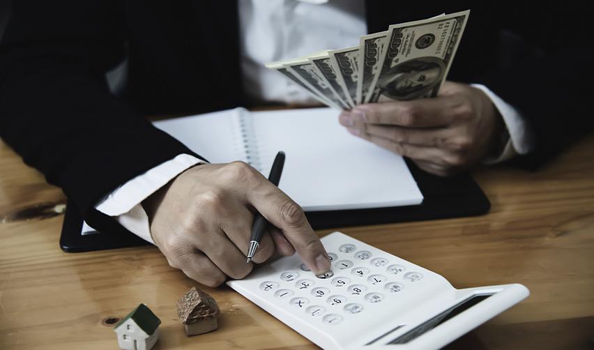 Investor calculating EB5 funding options with U.S. dollar bills, illustrating installment plans and financial strategies for meeting EB5 investment requirements.