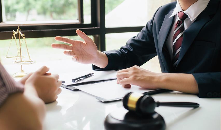 An EB5 immigration attorney discussing legal matters with a client, with a gavel, legal scales, and documents in view.