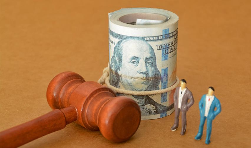 A gavel, a rolled stack of U.S. hundred-dollar bills, and two miniature business figures represent the legal framework and funding options for EB5 investors.