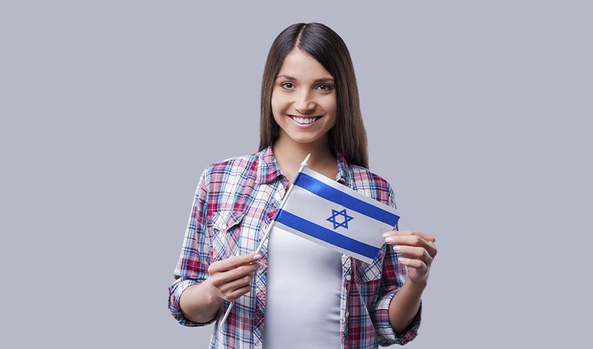 A young Israeli woman, smiling and holding an Israeli flag, symbolizes the journey of Israeli citizens seeking to apply for a Green Card through various U.S. immigration pathways.