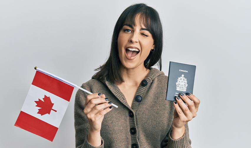 Happy woman holding a Canadian passport and waving a Canadian flag, illustrating the meaning of country of chargeability for Canadian residents seeking U.S. Green Cards via the EB5 visa.