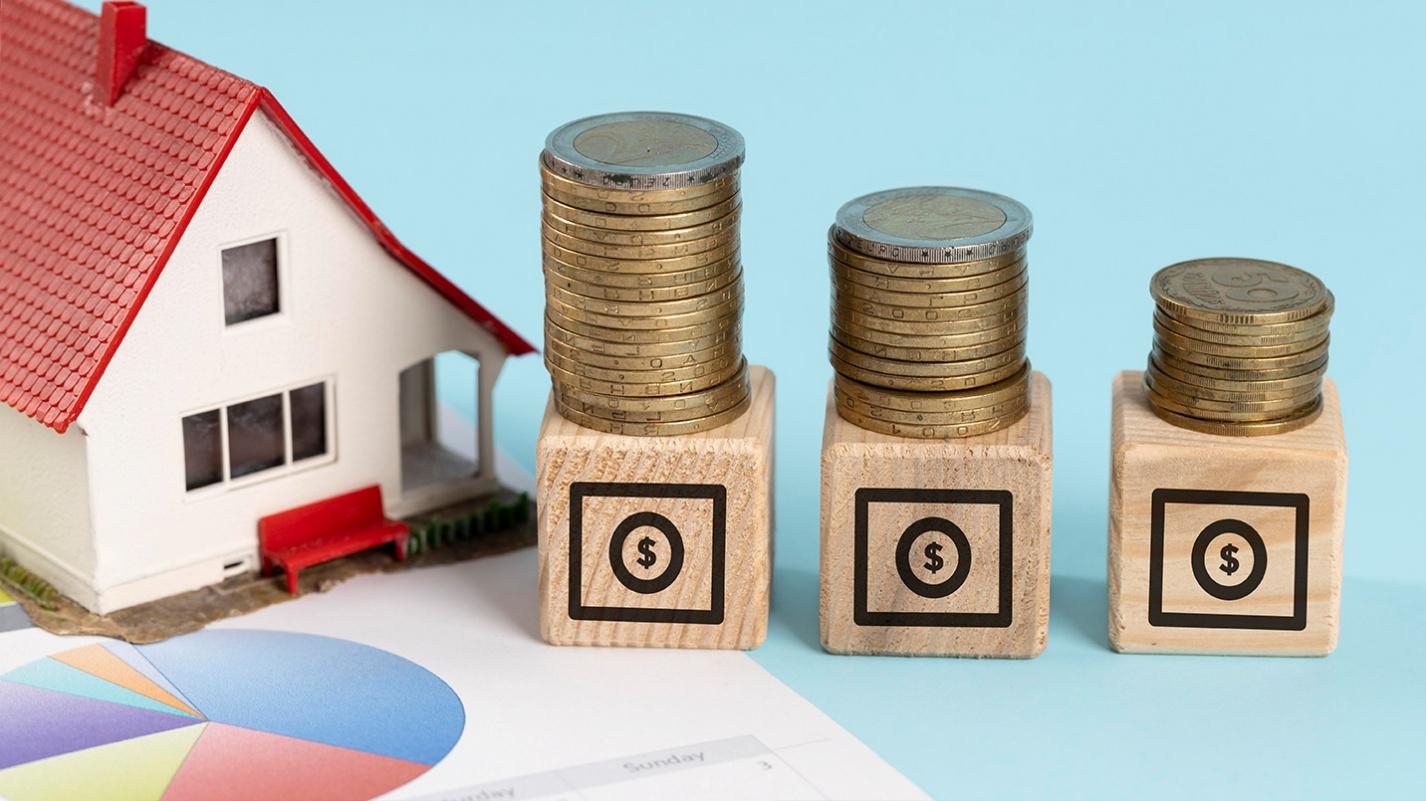 A financial planning concept featuring a model house, stacked coins, and investment charts, emphasizing key factors in deciding whether to rent or buy property in Puerto Rico. This image highlights property appreciation, mortgage costs, and long-term investment strategies.
