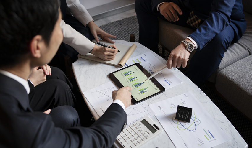 Group of business professionals analyzing investment charts on a tablet, discussing regional center projects and selecting real estate projects for EB5 investment.