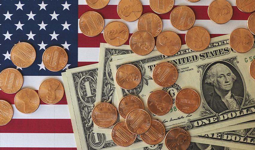 American coins scattered over dollar bills placed on a U.S. flag, symbolizing EB5 investment and economic contribution for U.S. residency.