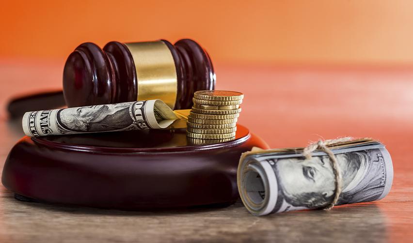 A gavel with rolled dollar bills and stacked coins, representing the legal requirements for proving the source and path of EB5 investment funds.