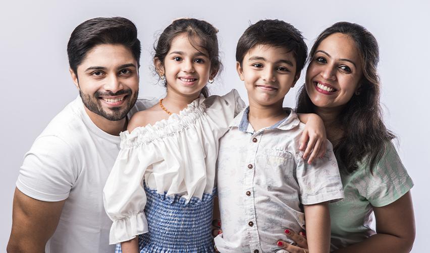 A happy family of four smiling at the camera, symbolizing EB5 investors planning to relocate to the U.S. through the EB5 visa program.