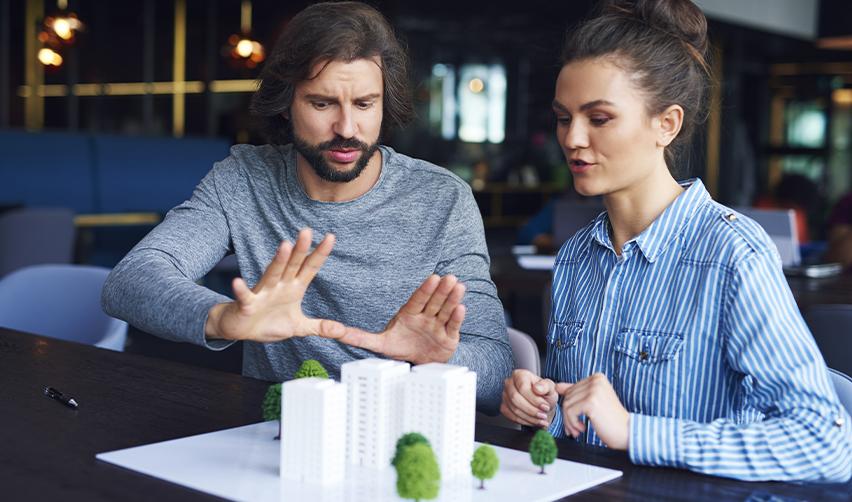Two professionals examining a scale model of a real estate project, symbolizing EB5 investors reviewing regional center development plans for U.S. Green Card eligibility.