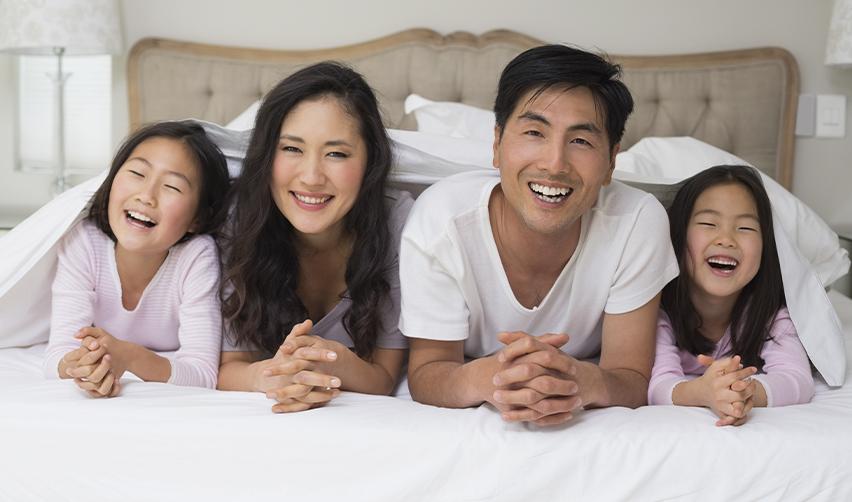 A happy EB5 investor family—parents and two young daughters—smiling together, symbolizing successful U.S. immigration through the EB5 Green Card program.