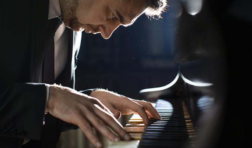 A concert pianist intensely focused on his performance, representing extraordinary ability professionals eligible for the EB-1A visa.