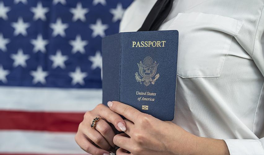Close-up of a person holding a U.S. passport against an American flag, highlighting the pathway to citizenship through EB5.