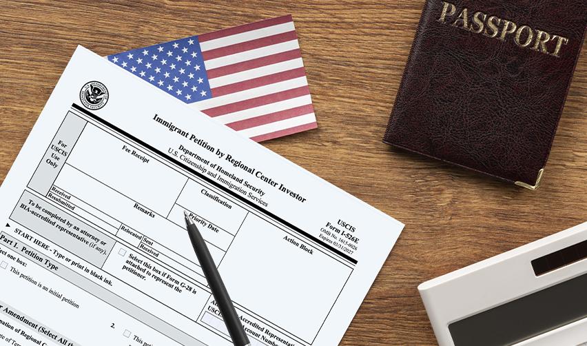 Close-up of EB5 Form I-526E with a U.S. passport and American flag, representing the paperwork stage of the EB5 visa application process.