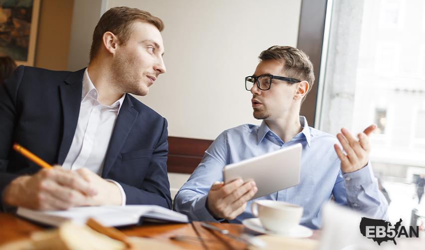 Two businessmen discussing opportunities over coffee, illustrating global networking benefits for EB5 investors or regional center industry experts like EB5AN helping EB5 green card applicants.
