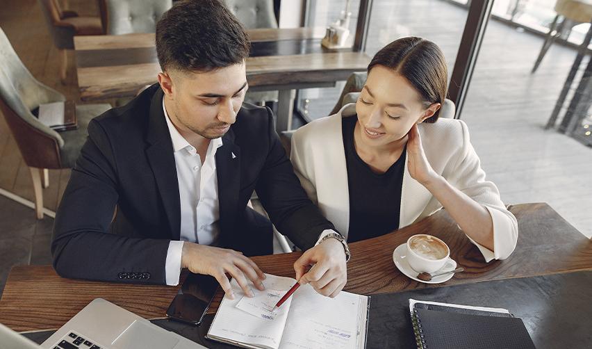 Two professionals in a business meeting, discussing investment strategies and EB5 project planning over coffee.